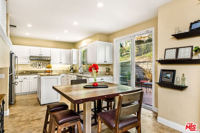 kitchen with appliances with stainless steel finishes, a center island, white cabinetry, sink, and stone counters