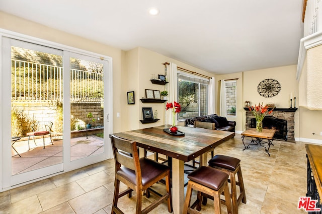 dining room featuring light tile patterned floors and a stone fireplace