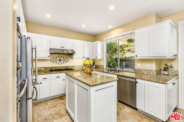 kitchen featuring light stone countertops, appliances with stainless steel finishes, sink, and a center island