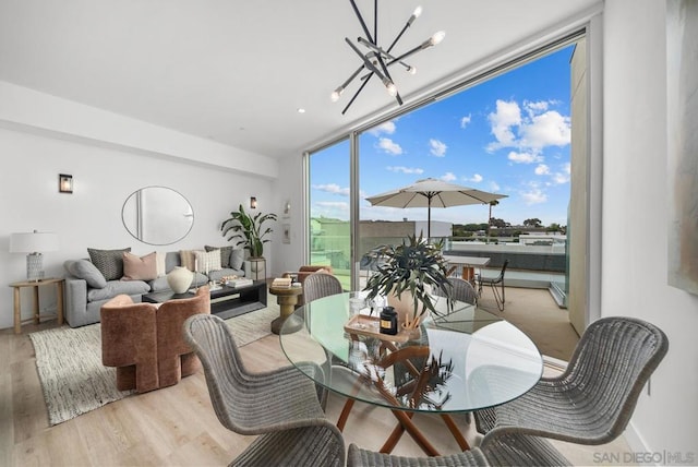 dining space with an inviting chandelier, floor to ceiling windows, and light wood-type flooring