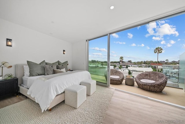 bedroom featuring access to exterior, hardwood / wood-style flooring, and a wall of windows