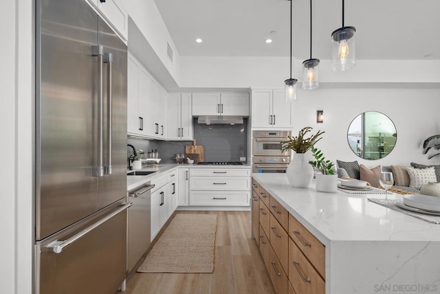 kitchen featuring white cabinetry, appliances with stainless steel finishes, light stone counters, and pendant lighting