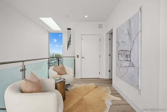 sitting room featuring floor to ceiling windows, a skylight, and light wood-type flooring