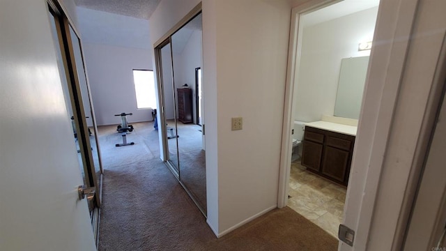 hallway with a textured ceiling and light carpet