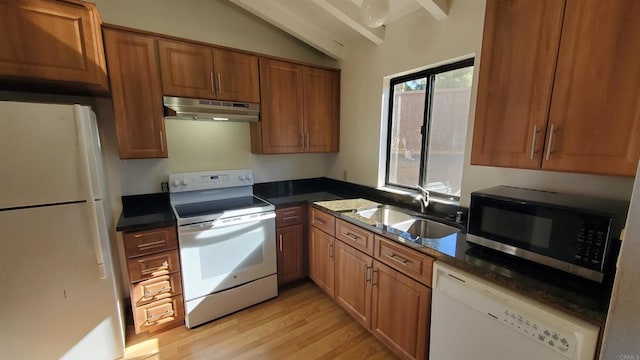 kitchen featuring white appliances, light wood-type flooring, dark stone countertops, vaulted ceiling, and sink