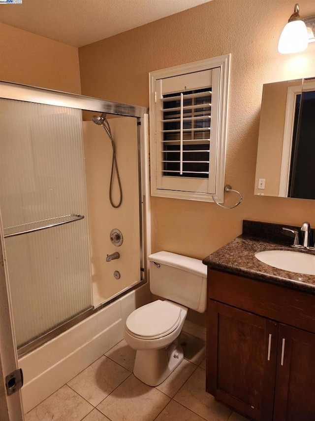 full bathroom featuring shower / bath combination with glass door, vanity, toilet, and tile patterned flooring