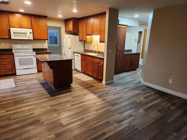 kitchen with dark wood-type flooring, sink, white appliances, and a kitchen island