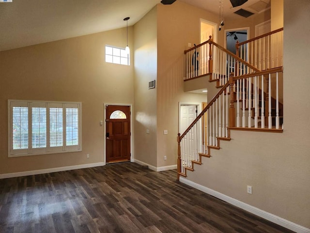 foyer with ceiling fan, dark hardwood / wood-style flooring, and a towering ceiling