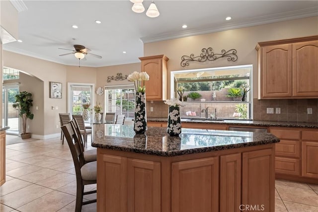 kitchen with light tile patterned floors, a center island, dark stone counters, and sink