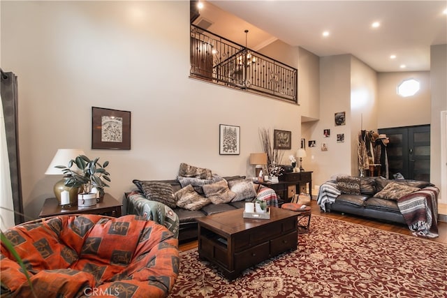 living room with a towering ceiling, wood-type flooring, and a notable chandelier