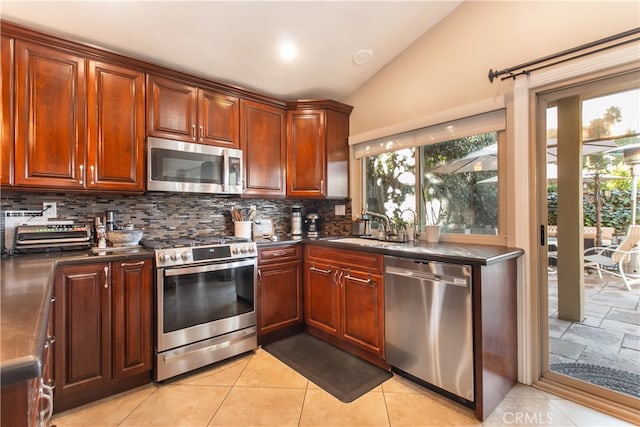 kitchen with vaulted ceiling, decorative backsplash, sink, light tile patterned flooring, and stainless steel appliances