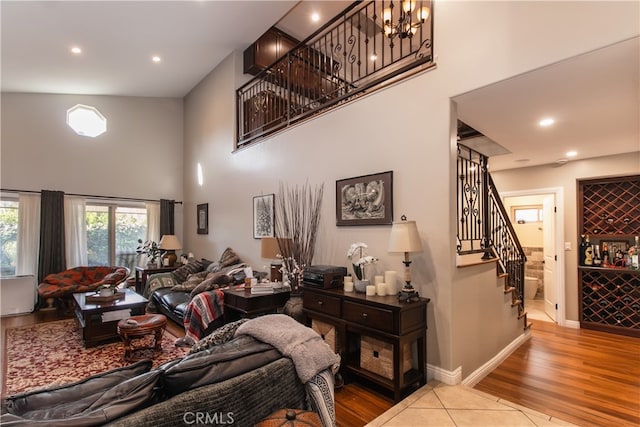 living room featuring an inviting chandelier, a high ceiling, and light hardwood / wood-style floors