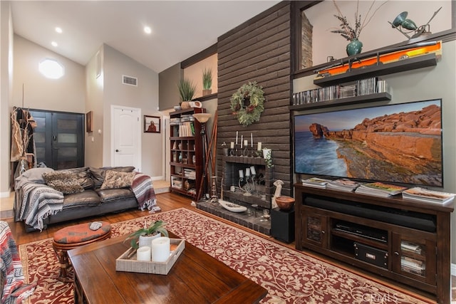 living room with high vaulted ceiling, hardwood / wood-style floors, and a fireplace