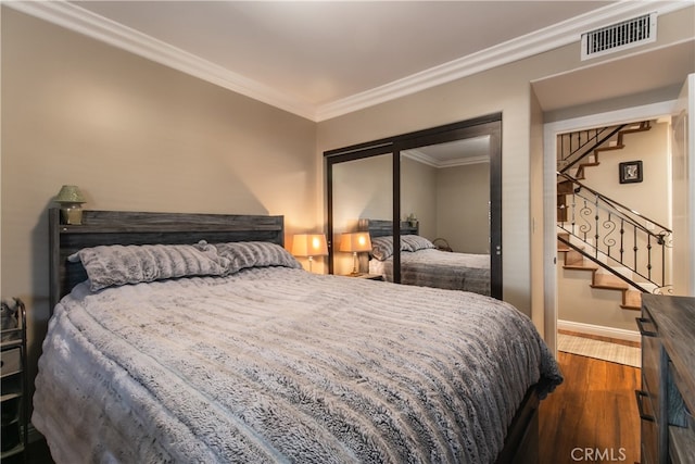 bedroom featuring a closet, dark hardwood / wood-style flooring, and crown molding