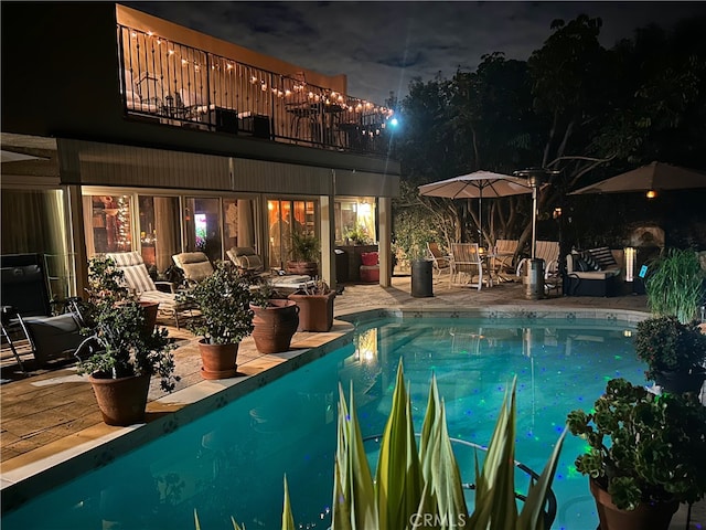 pool at twilight featuring a patio area