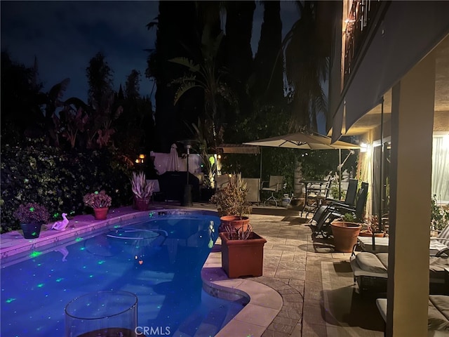 pool at twilight featuring a patio area