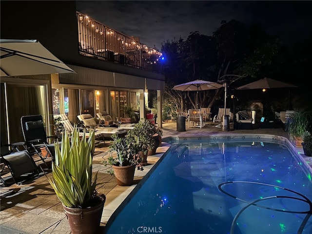 pool at twilight featuring a patio area