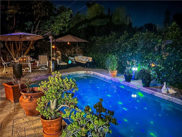 pool at twilight with a patio area