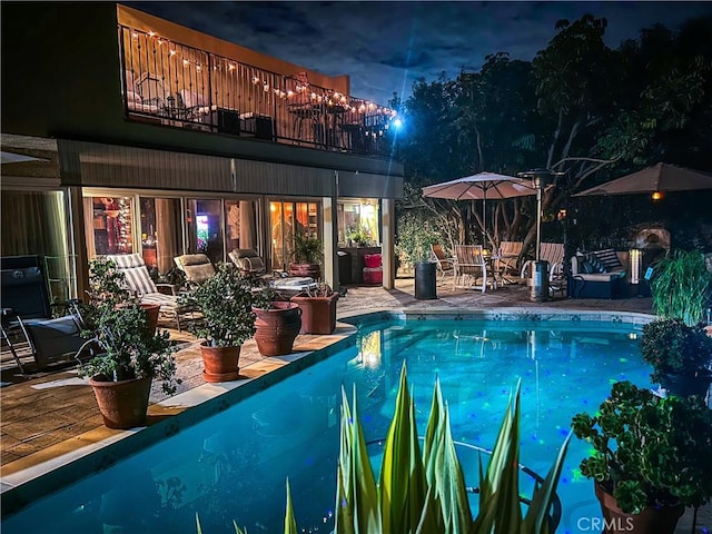 pool at twilight with a patio and an outdoor pool