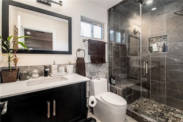 bathroom featuring tile walls, a stall shower, toilet, and vanity