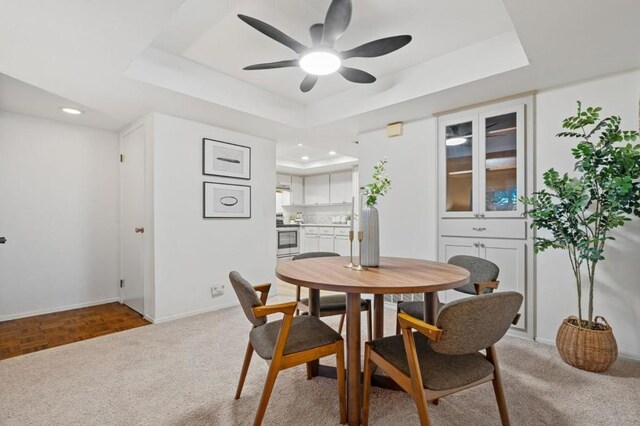 dining area featuring ceiling fan, a tray ceiling, and parquet floors