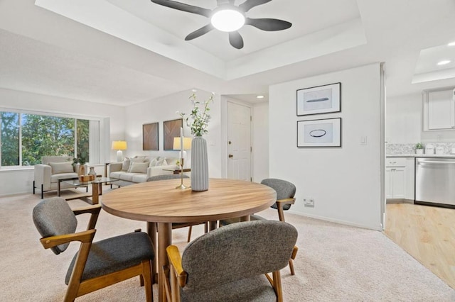 carpeted dining area featuring ceiling fan and a raised ceiling