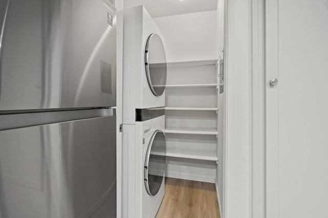 laundry area with stacked washer and dryer and light hardwood / wood-style floors