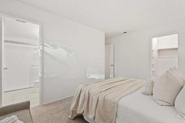 bedroom featuring light colored carpet, a spacious closet, and connected bathroom