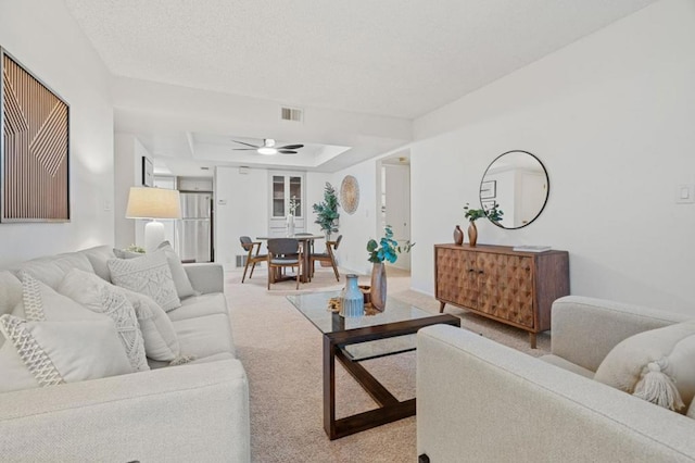 living room featuring ceiling fan, a tray ceiling, and carpet flooring