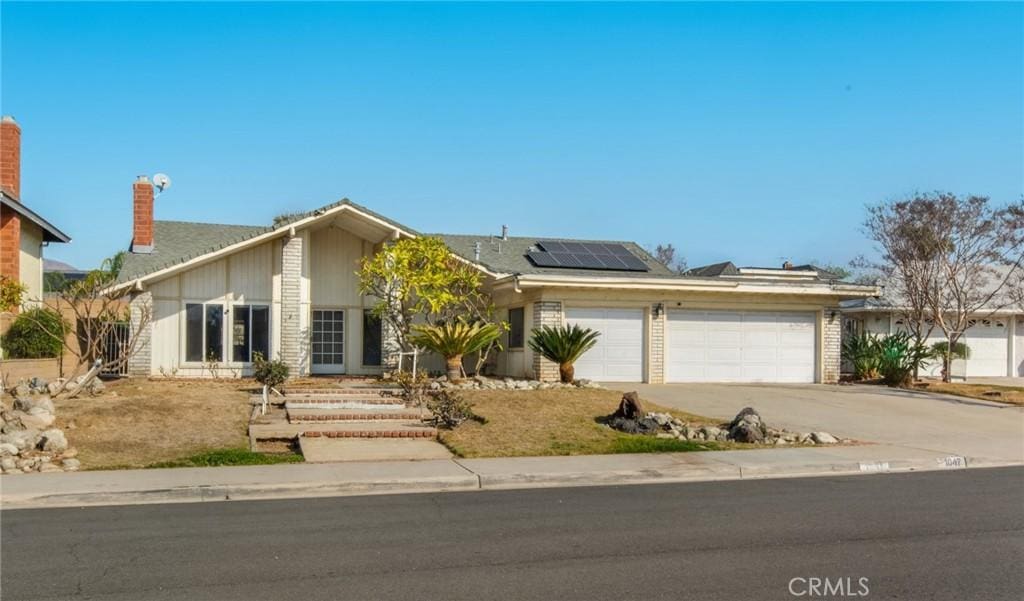 ranch-style house with a garage and solar panels