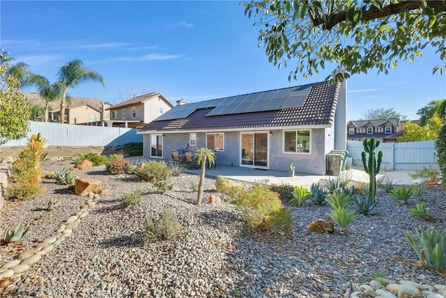 rear view of house featuring a patio area and solar panels