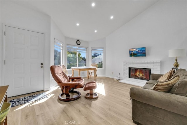 living room with a brick fireplace, light hardwood / wood-style flooring, and lofted ceiling