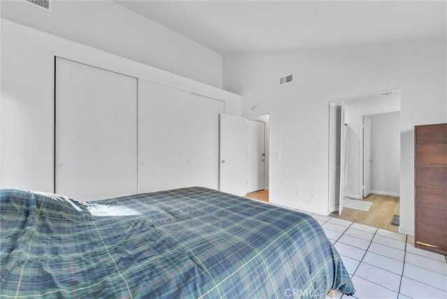 bedroom with a closet, light tile patterned floors, and lofted ceiling