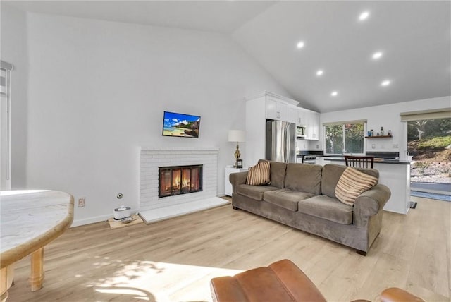 living room featuring high vaulted ceiling, light wood-type flooring, and a fireplace