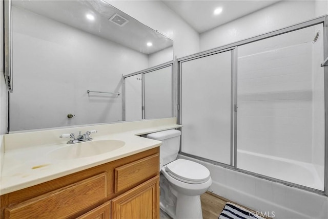 full bathroom featuring toilet, bath / shower combo with glass door, hardwood / wood-style flooring, and vanity