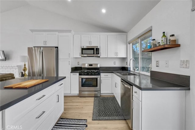 kitchen with sink, white cabinets, stainless steel appliances, and vaulted ceiling