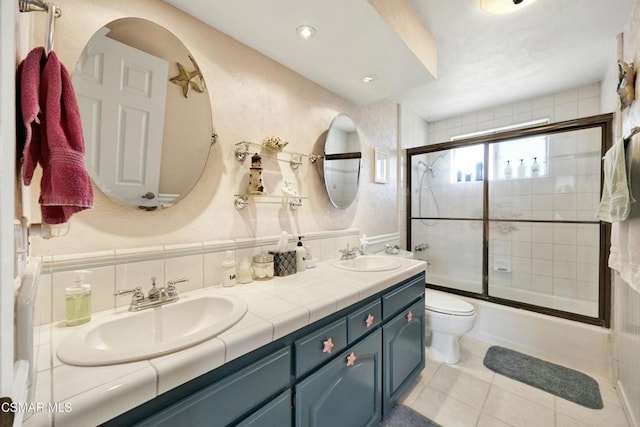 full bathroom with toilet, vanity, tile patterned floors, decorative backsplash, and shower / bath combination with glass door