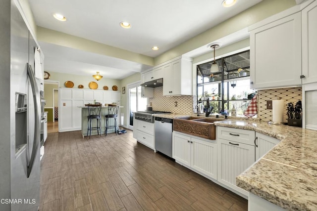 kitchen with dark wood-type flooring, white cabinetry, stainless steel appliances, decorative backsplash, and sink