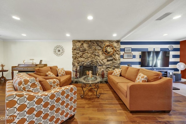 living room with wood-type flooring, crown molding, and a stone fireplace