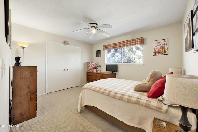 bedroom with ceiling fan, a closet, and light colored carpet