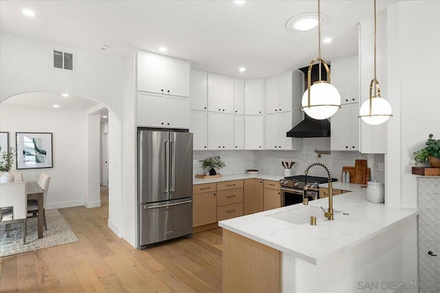 kitchen featuring high end appliances, decorative backsplash, pendant lighting, and white cabinets