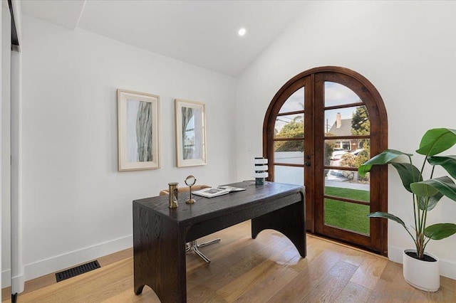 office space with french doors, vaulted ceiling, and light hardwood / wood-style flooring