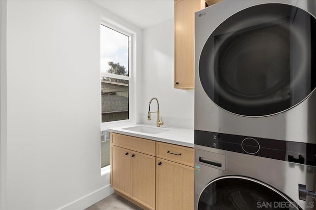 washroom with stacked washer / drying machine, sink, and cabinets