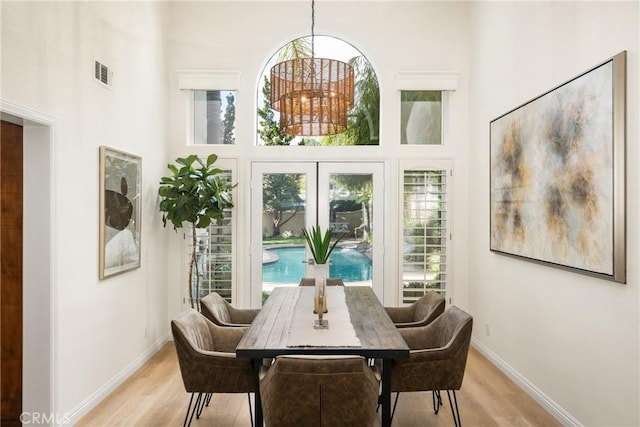 dining area featuring a high ceiling, a wealth of natural light, and light hardwood / wood-style flooring