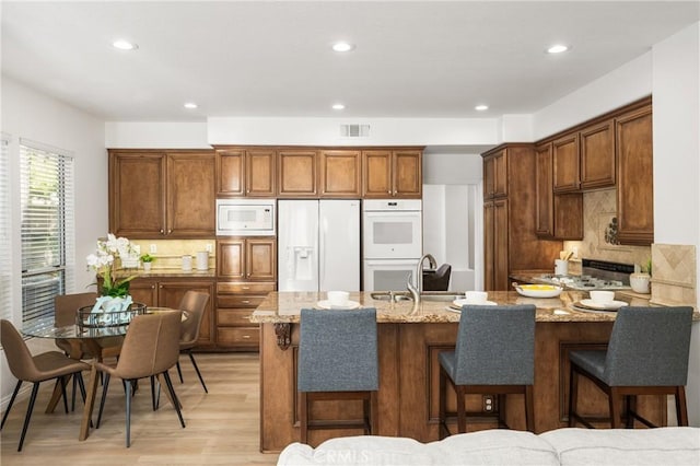 kitchen with sink, white appliances, light stone countertops, and a breakfast bar