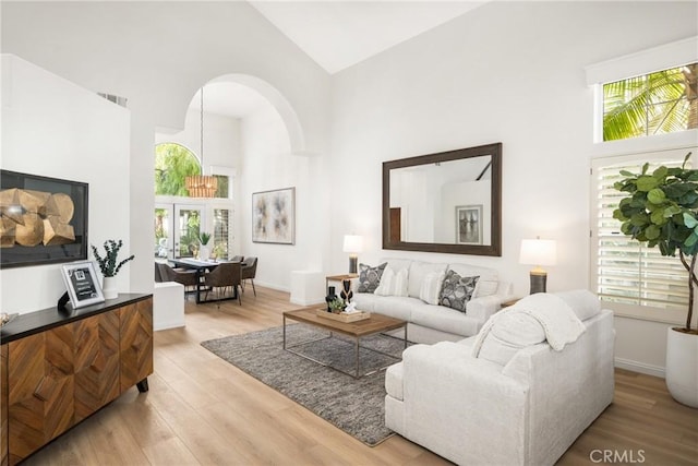 living room with plenty of natural light, high vaulted ceiling, and light hardwood / wood-style flooring