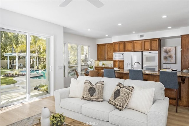 living room with ceiling fan and light wood-type flooring