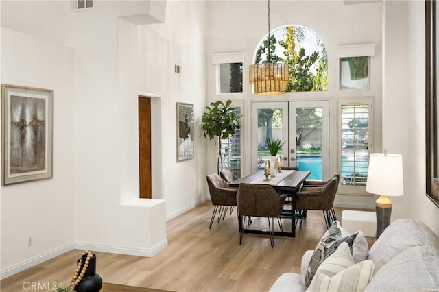 dining space with a towering ceiling and light wood-type flooring