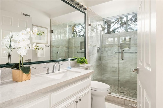 bathroom featuring a shower with door, vanity, and toilet