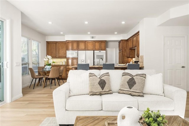 living room featuring sink and light hardwood / wood-style flooring